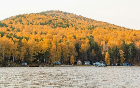 Beautiful lake Turgoyak in Russia against the background of a mountain covered with yellow autumn foliage. Autumn landscape