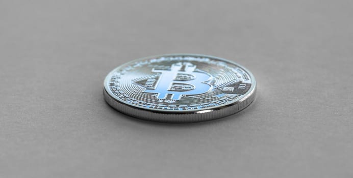 Bitcoin laying on flat surface. White metal coin