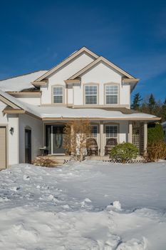 Big luxury house with front yard in snow. Residential house on winter sunny day