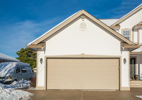 Wide garage door of luxury house with concrete driveway and RV wagon parked nearby. Residential house on winter sunny day