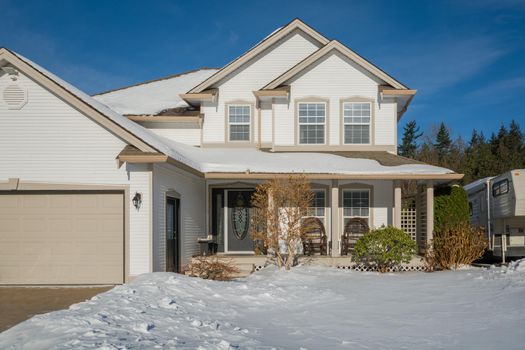 Big luxury house with front yard in snow. Residential house on winter sunny day