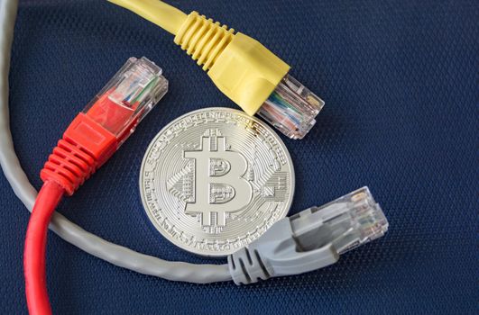 Metal coin of bitcoin with color ethernet plugs around