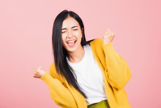 Happy Asian portrait beautiful cute young woman standing winning and surprised excited screaming open mouth raise hands, studio shot isolated pink background, Thai female wow with copy space