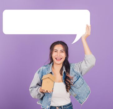Happy Asian portrait beautiful cute young woman wear denim excited smiling hold house model and empty speech bubble sign, studio shot isolated on purple background, broker female real estate insurance