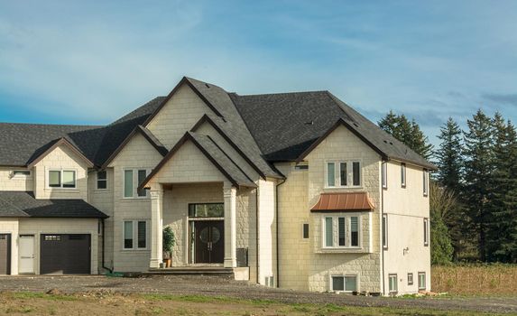 Giant new residential house with unpaved driveway in front