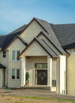 Entrance of new residential house with unpaved driveway in front