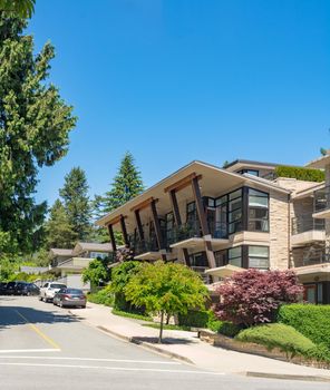 Brand new apartment building with cars parked on the street on sunny day in British Columbia, Canada.