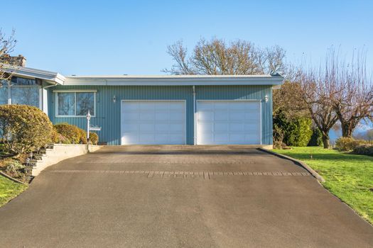 Double gates garage of big residential house with asphalt driveway in front