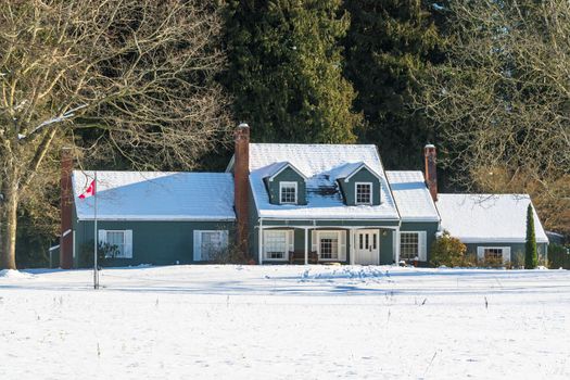 Big farmers house with spacious front yard at winter season. Residential house in snow on a sunny day
