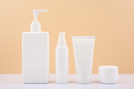 Set of cosmetic for skin care in white tubes on white table against bright beige background. Concept of beauty treatment and skin care products