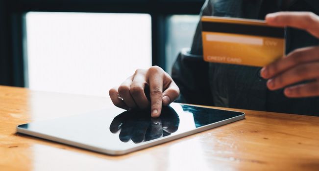 Close up woman at home shopping online with credit card and digital tablet.