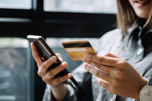Close up woman at home shopping online with credit card and smart phone.