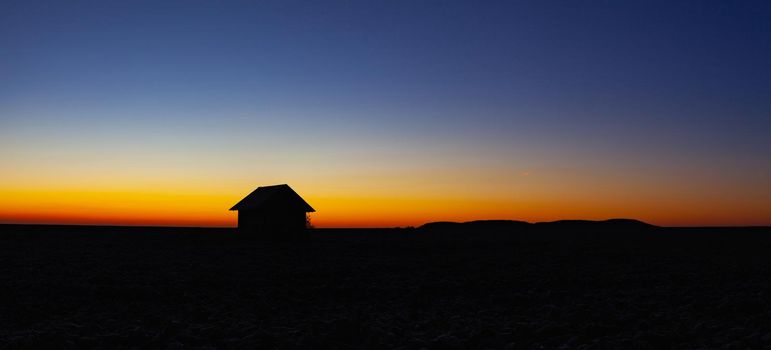 Old barn on the field in the blue hour.