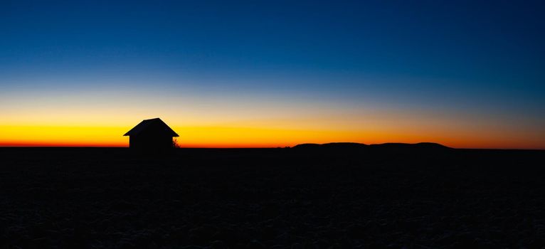 Old barn on the field in the blue hour.