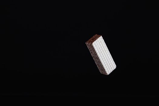 One levitating chocolate wafer on a black background