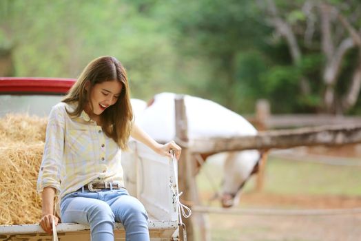A woman in a cowgirl style sits in a horse ranch with a western farm environment.