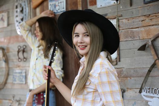 A woman in a cowgirl style sits in a horse ranch with a western farm environment.