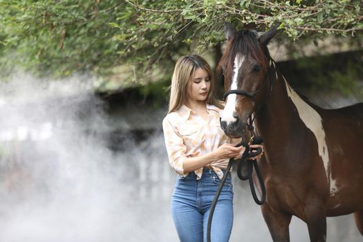A woman in a cowgirl style sits in a horse ranch with a western farm environment.