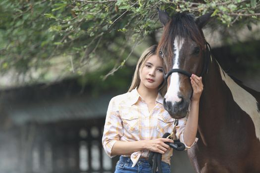A woman in a cowgirl style sits in a horse ranch with a western farm environment.