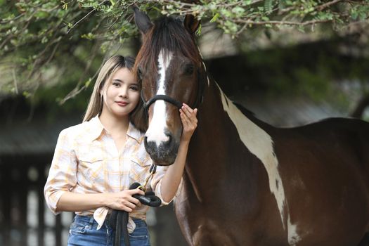 A woman in a cowgirl style sits in a horse ranch with a western farm environment.