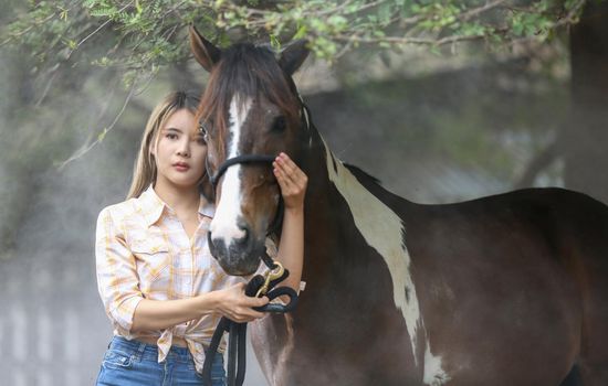 A woman in a cowgirl style sits in a horse ranch with a western farm environment.