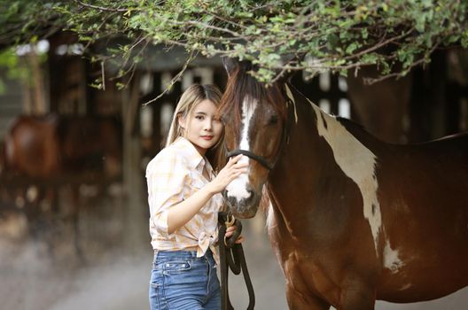 A woman in a cowgirl style sits in a horse ranch with a western farm environment.