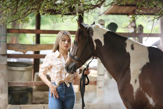 A woman in a cowgirl style sits in a horse ranch with a western farm environment.