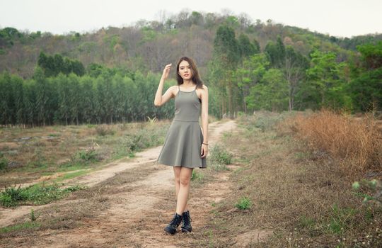 A beautiful woman with long hair in a dress sitting on a meadow and flowers in the evening light.