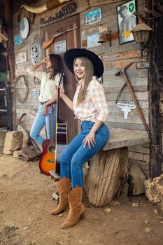 A woman in a cowgirl style sits in a horse ranch with a western farm environment.