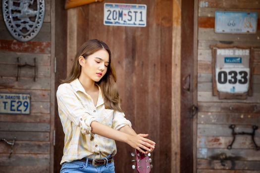 A woman in a cowgirl style sits in a horse ranch with a western farm environment.