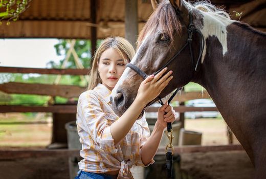 A woman in a cowgirl style sits in a horse ranch with a western farm environment.