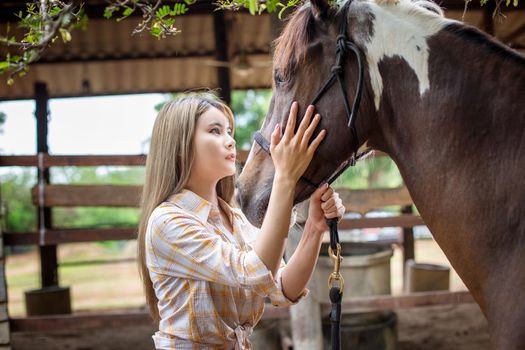 A woman in a cowgirl style sits in a horse ranch with a western farm environment.
