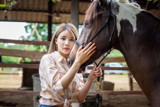 A woman in a cowgirl style sits in a horse ranch with a western farm environment.