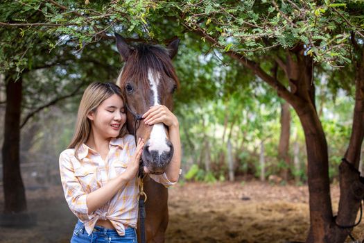 A woman in a cowgirl style sits in a horse ranch with a western farm environment.