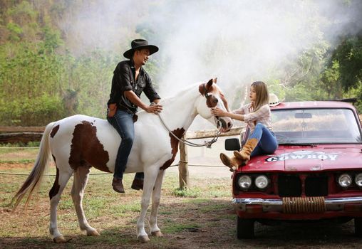 A woman in a cowgirl style sits in a horse ranch with a western farm environment.