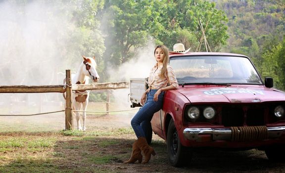 A woman in a cowgirl style sits in a horse ranch with a western farm environment.
