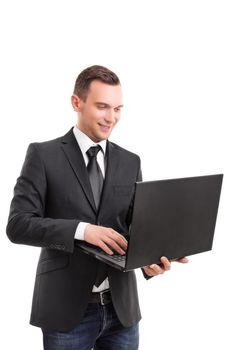 Portrait of a young attractive businessman in a suit jacket holding a laptop in hands reading, writing something and smiling, isolated on white background.