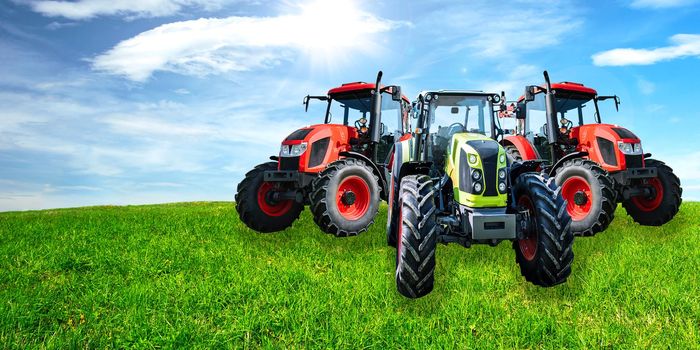 Agricultural advertisement banner - group of new and modern generic tractors on a green meadow in sunny day (mixed).