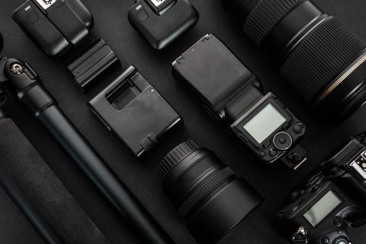 Large collection of professional and modern photographic equipment on a black background (low key).