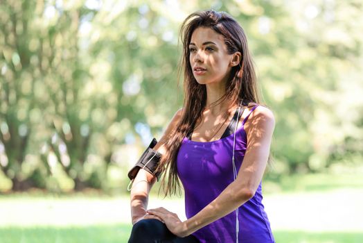 Portrait of a beautiful young girl stretching before jogging in the park on a sunny day