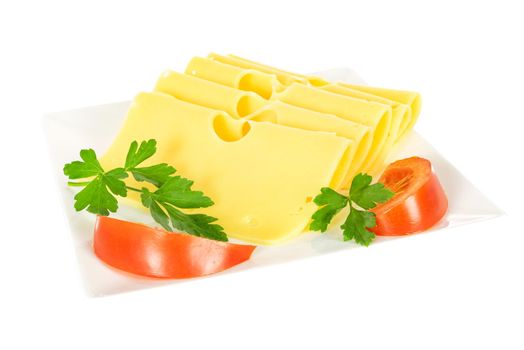 Pieces of fresh yellow cheese with parsley and tomatoes on a plate isolated on a white background in close-up.