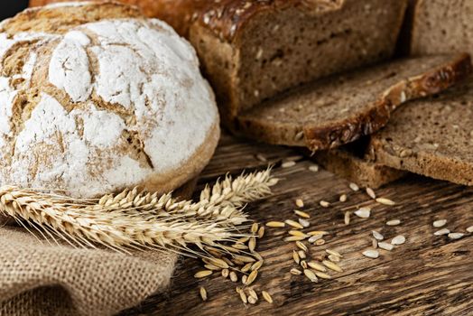 Group of dark breads with wheat, sunflower and rye grains on a wooden vintage table.