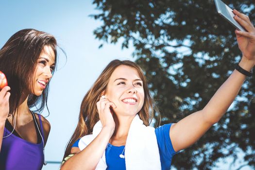 Millennials lifestyle concept - two sports girls take a selfie and smile while training outdoors on a sunny day ( vintage effect)