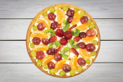 Top view of a fresh homemade multi-fruit tart cake on a wooden old table (high details).