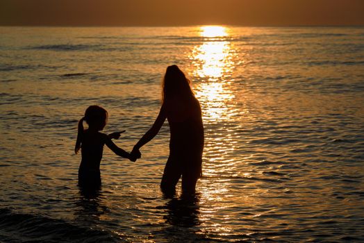 Young girls on the seashore during a picturesque sunset