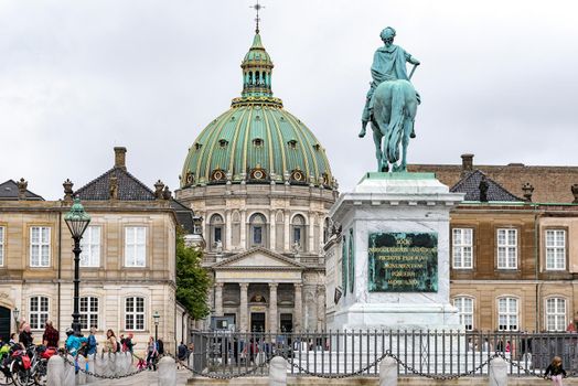 Copenhagen, Denmark - July 24, 2017: Tourists visiting Amalienborg Palace Square in Copenhagen with the statue of King Frederick V and Marble Church on the background.