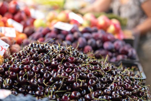 Fresh cherries and other fruits for sale in a traditional farmer market in close-up ( selective focus).