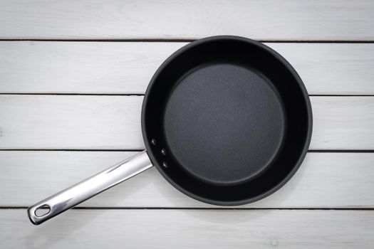 Culinary template - top view of an empty pan on a white wooden plank background. 