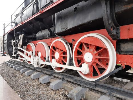 Wheels of an old steam locomotive on rails close-up.