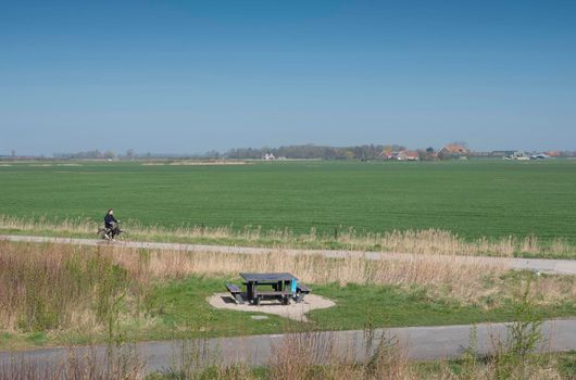 middelburg, netherlands, 31 march 2021: boy rides bike on country road near farms on countryside of walcheren near middelburg in dutch province of zeeland in the netherlands